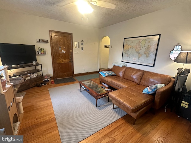 living room featuring light hardwood / wood-style flooring, a textured ceiling, and ceiling fan