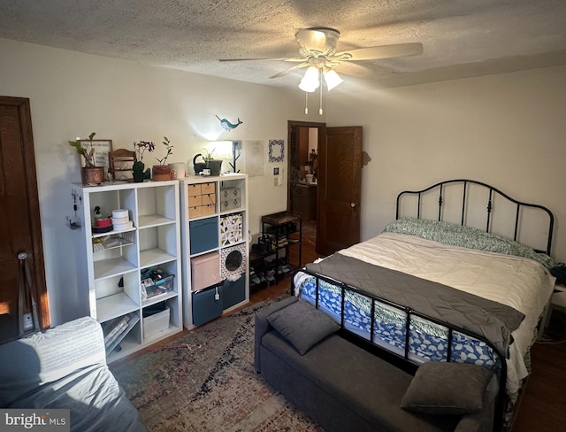 bedroom with ceiling fan, a textured ceiling, and dark hardwood / wood-style floors