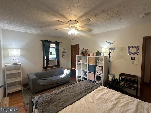 bedroom featuring cooling unit, a textured ceiling, wood-type flooring, and ceiling fan