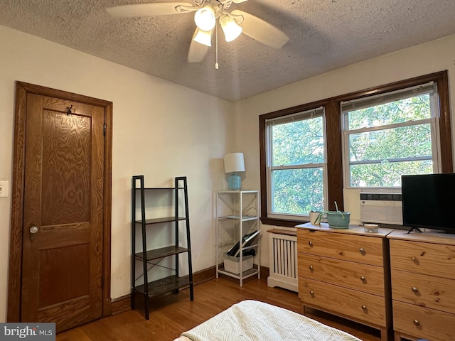 bedroom featuring a textured ceiling, radiator, dark hardwood / wood-style floors, and ceiling fan