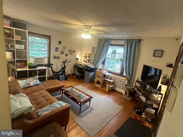 living room featuring wood-type flooring, a healthy amount of sunlight, and ceiling fan