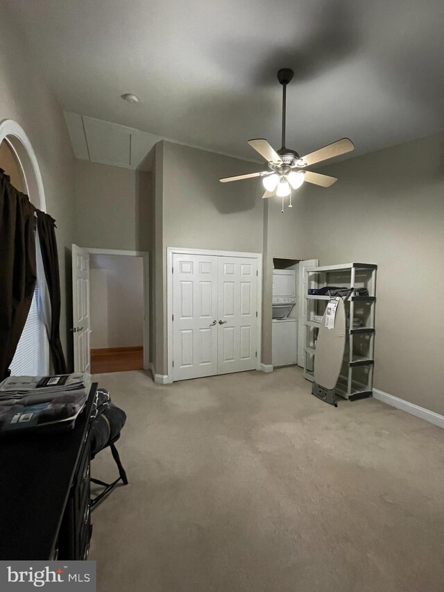 unfurnished bedroom featuring stacked washer / drying machine, light colored carpet, and ceiling fan