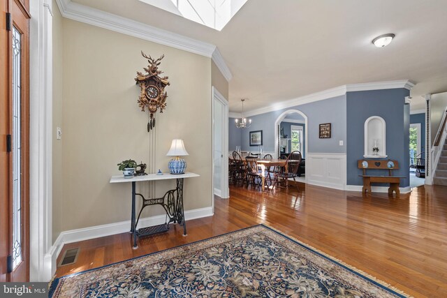 foyer with crown molding, a notable chandelier, and wood-type flooring