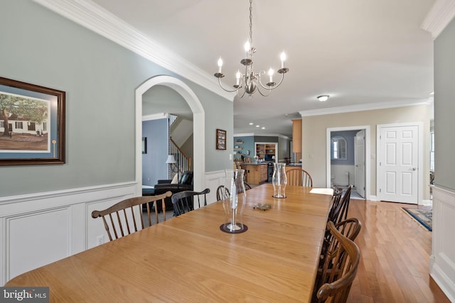 dining area with crown molding, a chandelier, and light hardwood / wood-style floors