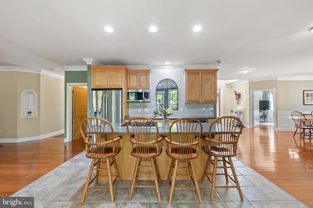 kitchen with appliances with stainless steel finishes, light hardwood / wood-style flooring, decorative backsplash, and ornamental molding