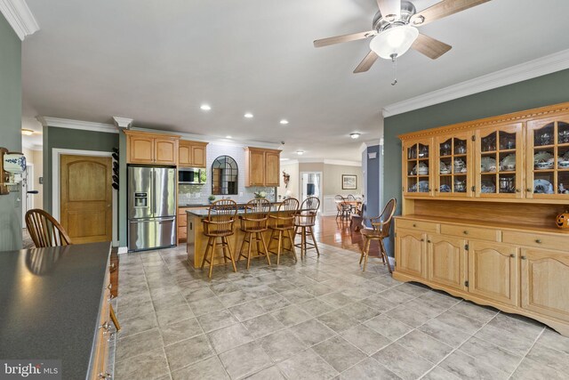 kitchen featuring a kitchen island, a kitchen breakfast bar, stainless steel appliances, backsplash, and ornamental molding