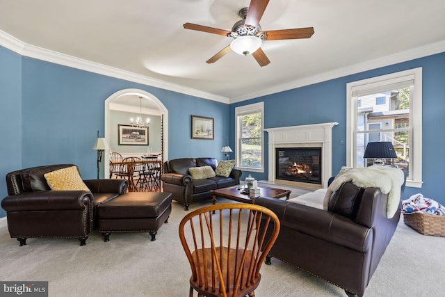 carpeted living room featuring ornamental molding and ceiling fan with notable chandelier