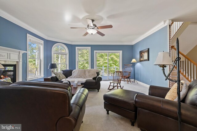 living room with ornamental molding, a premium fireplace, light colored carpet, and ceiling fan