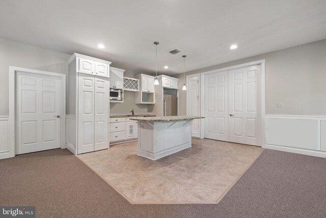 kitchen with a center island, pendant lighting, white cabinetry, light colored carpet, and appliances with stainless steel finishes