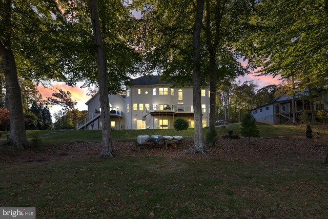 back house at dusk featuring a yard