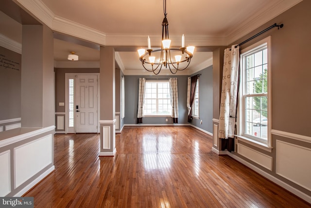 entrance foyer featuring a notable chandelier, plenty of natural light, wood-type flooring, and crown molding