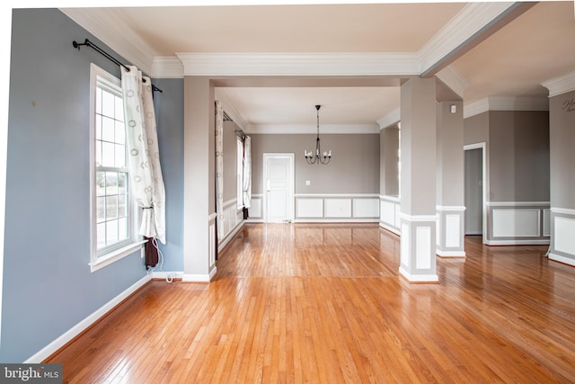 unfurnished living room with ornamental molding, a notable chandelier, and light wood-type flooring