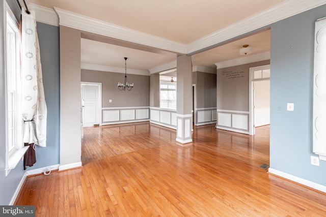 spare room featuring a notable chandelier, light hardwood / wood-style floors, and crown molding