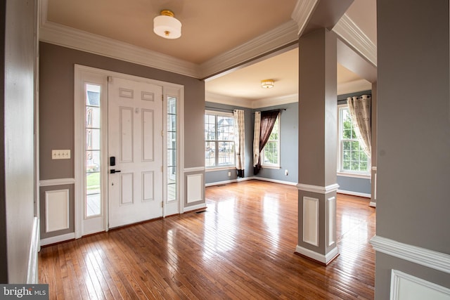 foyer entrance featuring decorative columns, crown molding, and hardwood / wood-style flooring