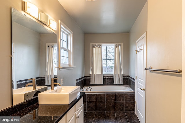 bathroom with tile patterned flooring, vanity, a healthy amount of sunlight, and tiled tub