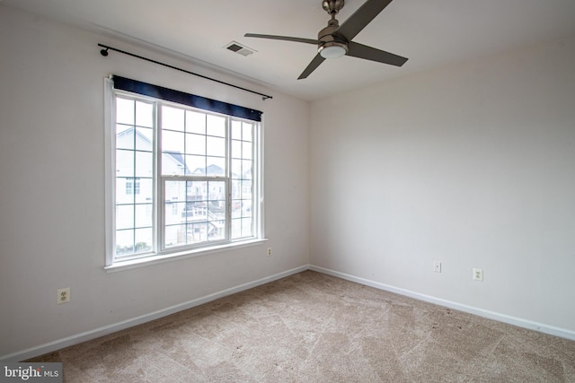 empty room featuring ceiling fan, light colored carpet, and a wealth of natural light