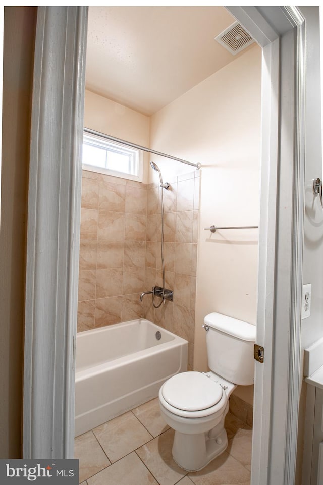 bathroom with tile patterned flooring, tiled shower / bath combo, and toilet