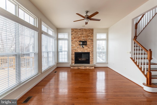 unfurnished living room featuring hardwood / wood-style floors, ceiling fan, and a fireplace