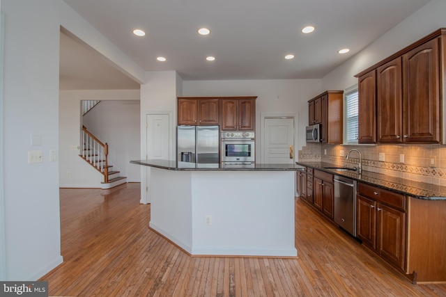 kitchen with appliances with stainless steel finishes, light wood-type flooring, and a kitchen island