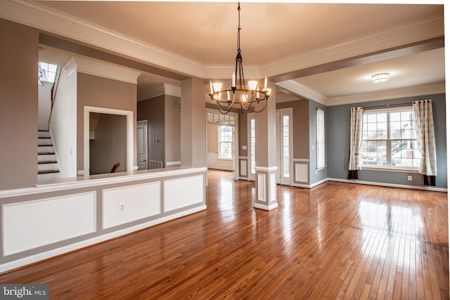 unfurnished dining area featuring crown molding, wood-type flooring, and an inviting chandelier