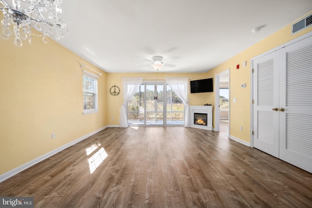 unfurnished living room featuring dark wood-type flooring and ceiling fan with notable chandelier