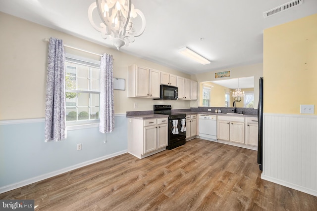 kitchen with black appliances, light hardwood / wood-style flooring, decorative light fixtures, and a chandelier