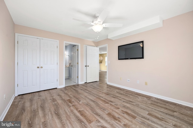 unfurnished bedroom with light hardwood / wood-style floors, ensuite bathroom, and ceiling fan