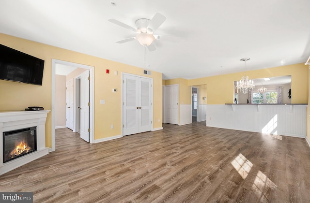 unfurnished living room with wood-type flooring and ceiling fan with notable chandelier