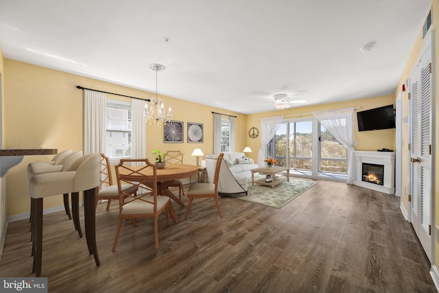 living room featuring dark wood-type flooring and ceiling fan with notable chandelier