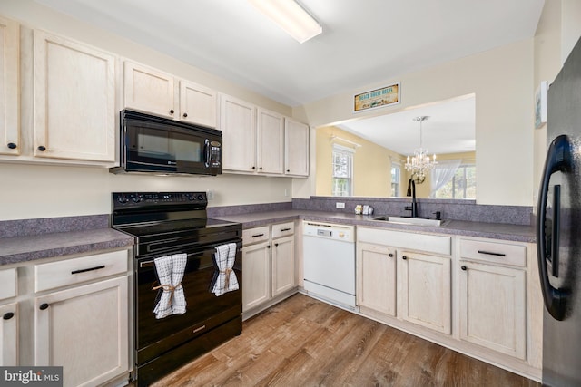 kitchen with light hardwood / wood-style flooring, sink, black appliances, pendant lighting, and an inviting chandelier