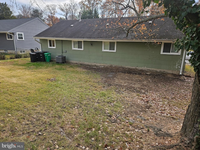 rear view of property with central AC and a lawn