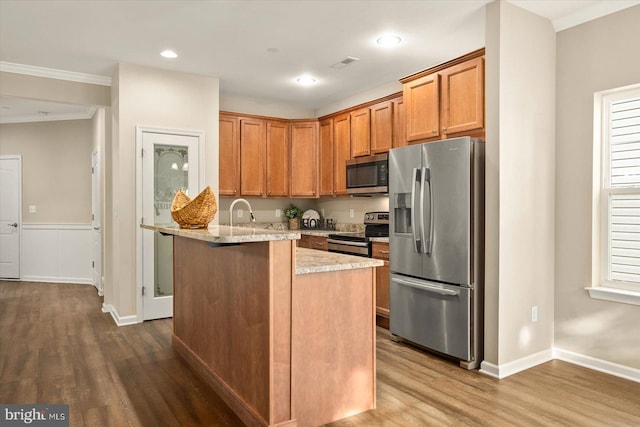 kitchen with crown molding, light stone countertops, stainless steel appliances, and wood-type flooring