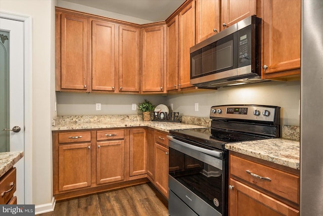 kitchen featuring stainless steel appliances, light stone countertops, and dark hardwood / wood-style flooring