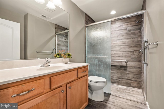 bathroom featuring vanity, toilet, hardwood / wood-style flooring, and a shower with door