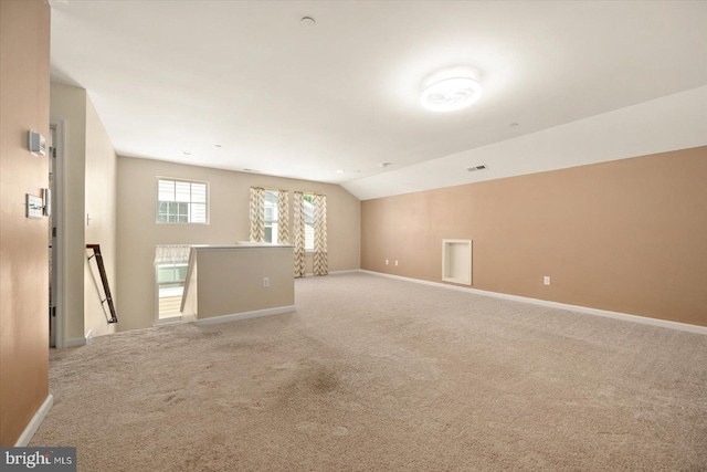 carpeted empty room featuring vaulted ceiling