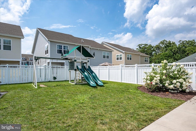 back of house featuring a yard and a playground