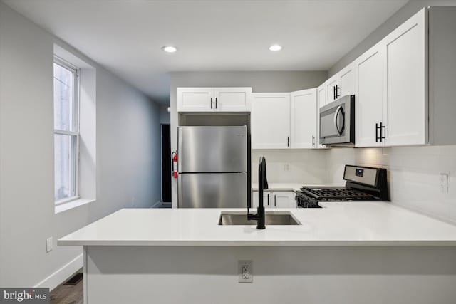 kitchen with appliances with stainless steel finishes, kitchen peninsula, and white cabinets