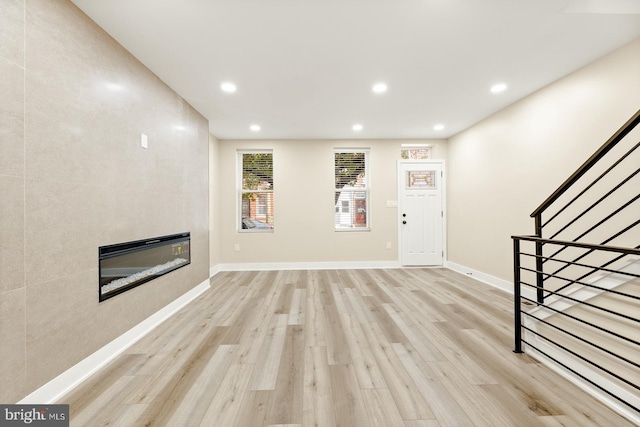 unfurnished living room with a fireplace and light wood-type flooring