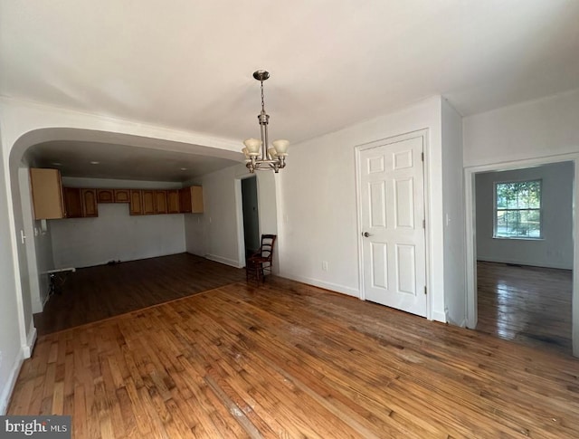 unfurnished living room with hardwood / wood-style floors and a chandelier