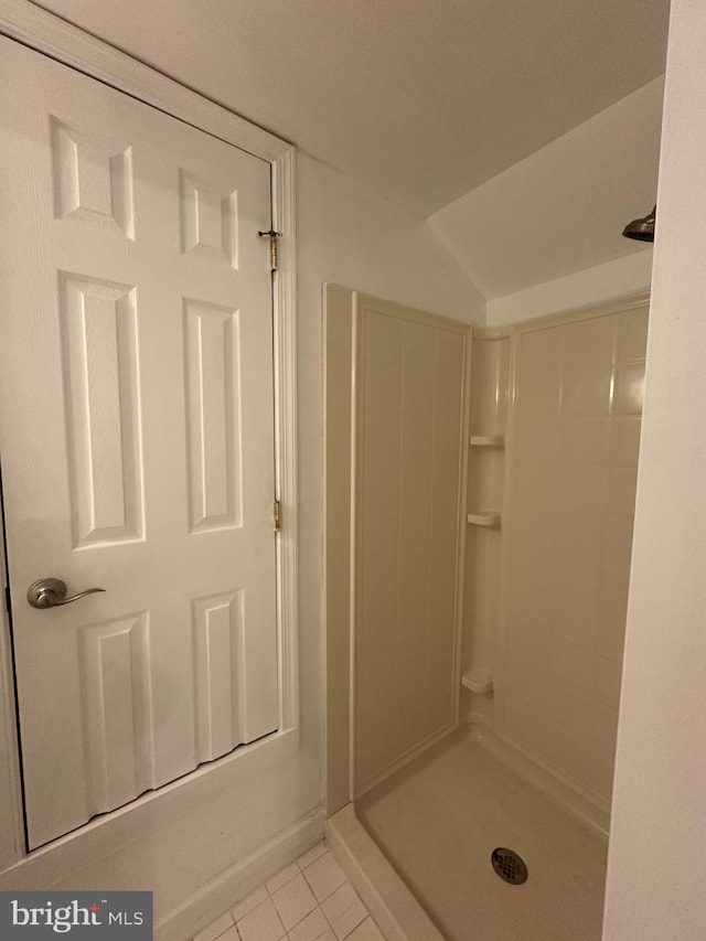 bathroom with tiled shower, lofted ceiling, and tile patterned floors