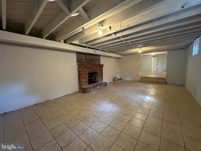 basement featuring light tile patterned floors and a brick fireplace