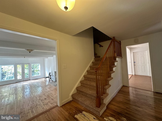 stairs with hardwood / wood-style floors and french doors