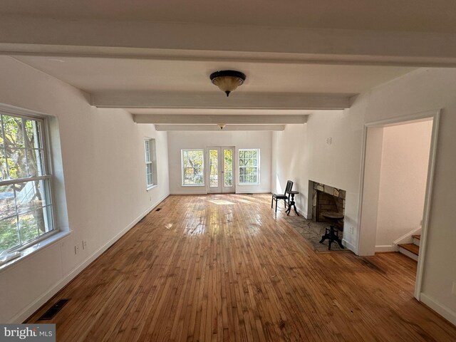 unfurnished living room with french doors, beam ceiling, and hardwood / wood-style flooring