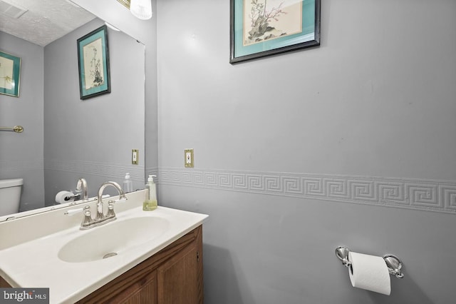 bathroom featuring vanity, toilet, and a textured ceiling