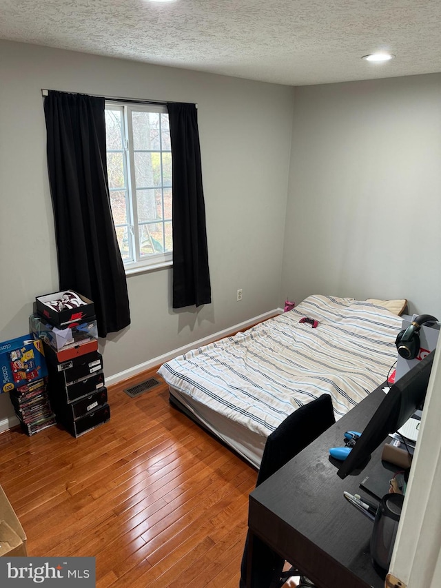 bedroom featuring wood-type flooring and a textured ceiling