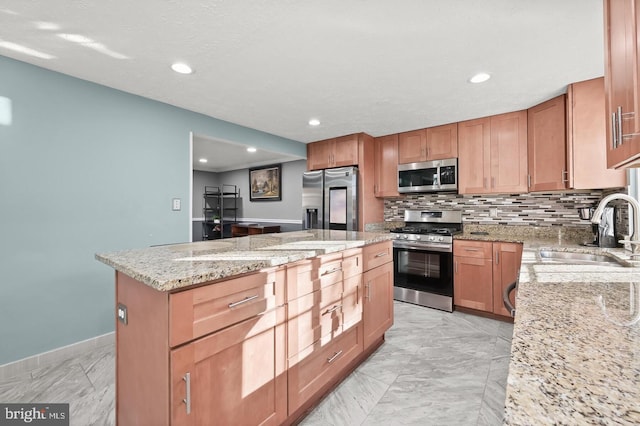 kitchen featuring light stone countertops, sink, a center island, decorative backsplash, and appliances with stainless steel finishes