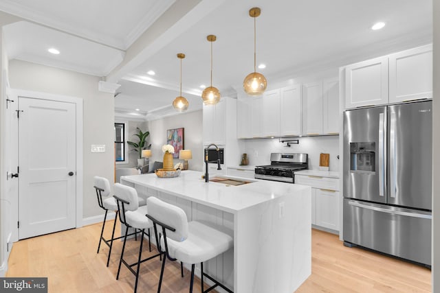 kitchen with sink, stainless steel appliances, white cabinets, light stone counters, and a kitchen island with sink