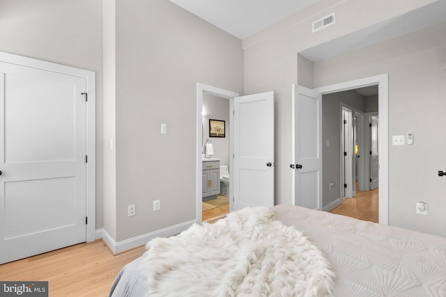 bedroom with ensuite bathroom and light hardwood / wood-style flooring