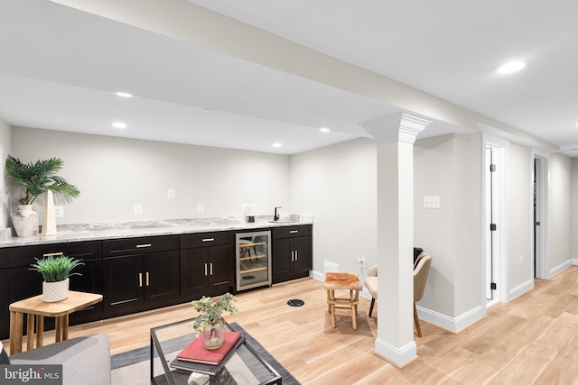 living room with light hardwood / wood-style flooring, wet bar, ornate columns, and beverage cooler