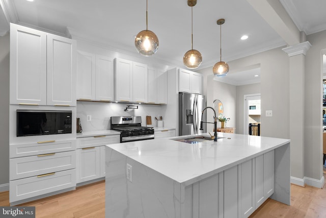 kitchen with light stone countertops, appliances with stainless steel finishes, a kitchen island with sink, and white cabinetry